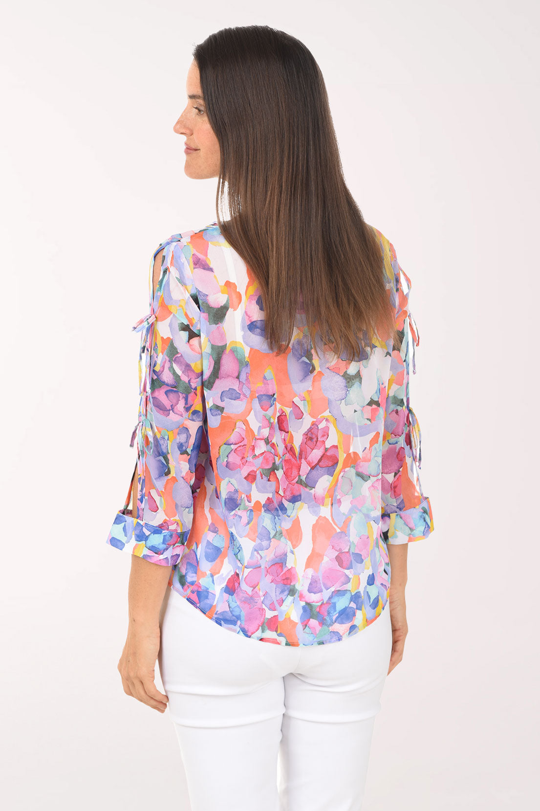 Woman wearing a colorful floral blouse against a white background