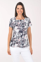 Woman wearing a patterned top and white pants on a white background