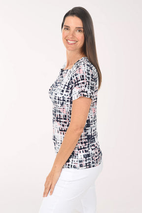 Woman wearing a patterned top and white pants on a white background
