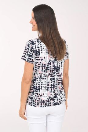 Woman wearing a patterned top and white pants on a white background