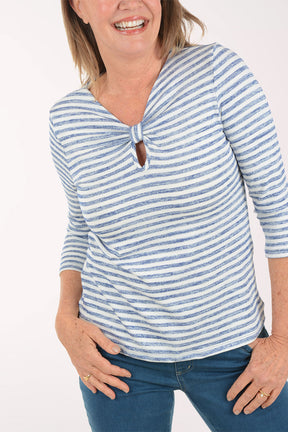 Woman wearing a blue and white striped top with a knot detail on a white background