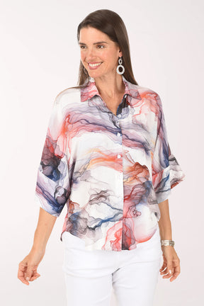 Woman wearing a colorful abstract patterned blouse on a white background
