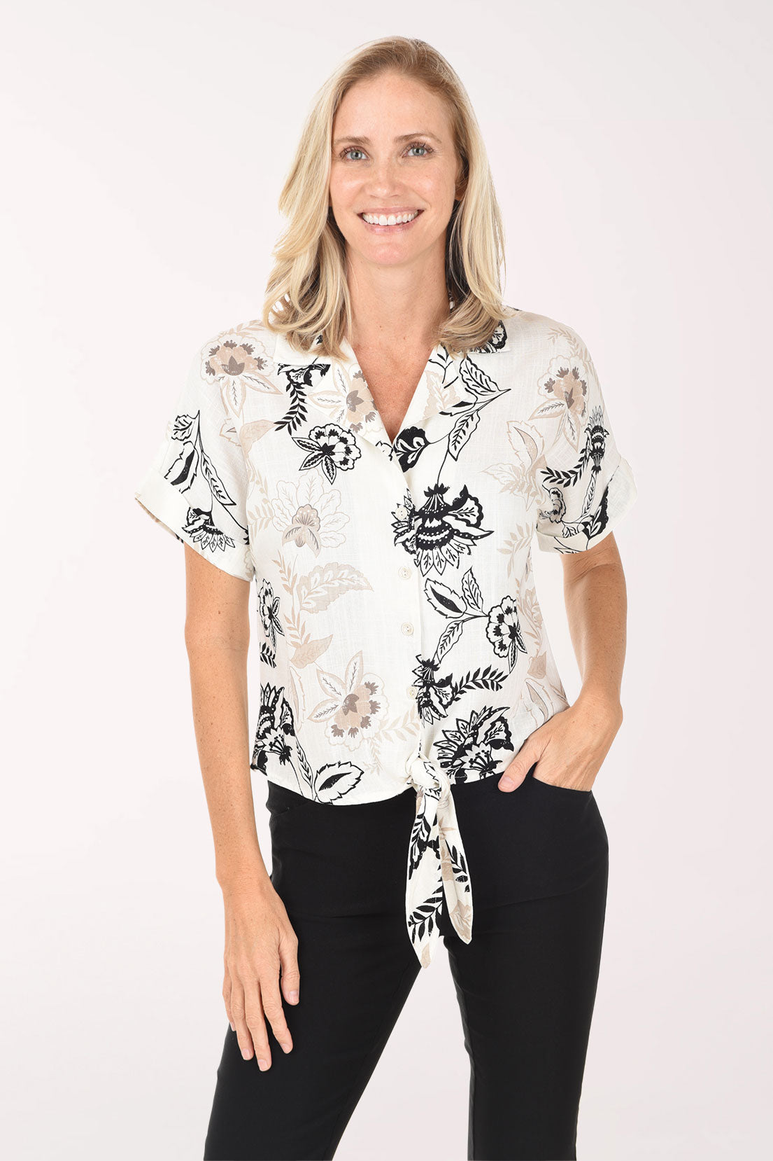 Woman wearing a white blouse with black floral patterns on a white background