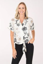 Woman wearing a white blouse with black floral patterns on a white background