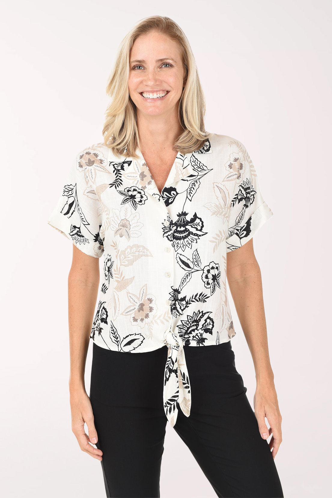 Woman wearing a white blouse with black floral patterns on a white background