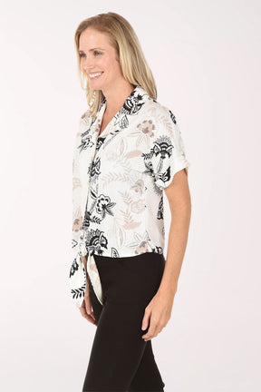 Woman wearing a white blouse with black floral patterns on a white background