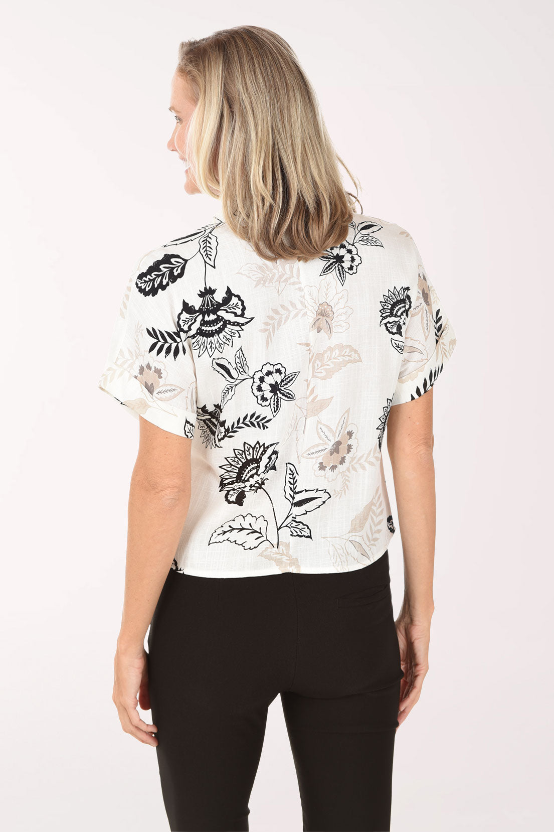 Woman wearing a white blouse with black floral patterns on a white background