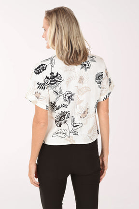 Woman wearing a white blouse with black floral patterns on a white background