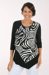A woman modeling a black three-quarter sleeve top with a bold black and white zebra and leopard print pattern on the front panel, paired with white pants, against a plain white studio background.