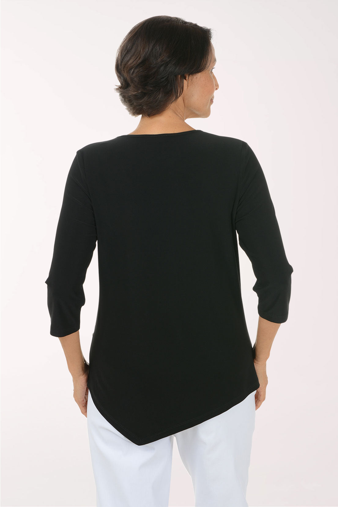 A woman modeling a black three-quarter sleeve top with a bold black and white zebra and leopard print pattern on the front panel, paired with white pants, against a plain white studio background.