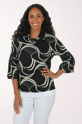 A woman modeling a black three-quarter sleeve blouse with a white abstract wavy pattern, paired with white pants, against a plain white studio background.