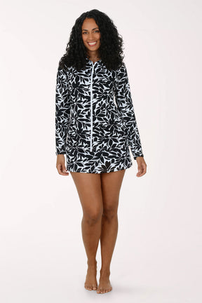 Woman wearing a black and white floral long-sleeve rash guard and matching bottoms on a white background