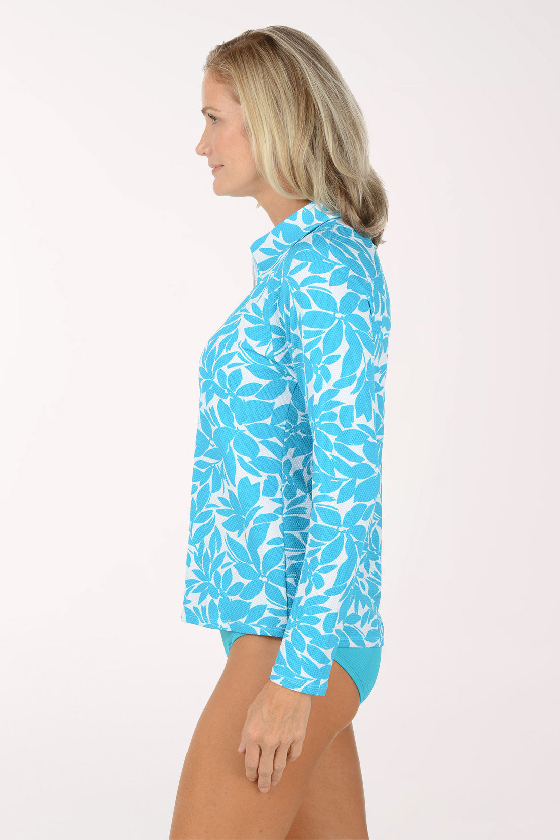 Woman wearing a blue floral long-sleeve rash guard and matching bottoms on a white background