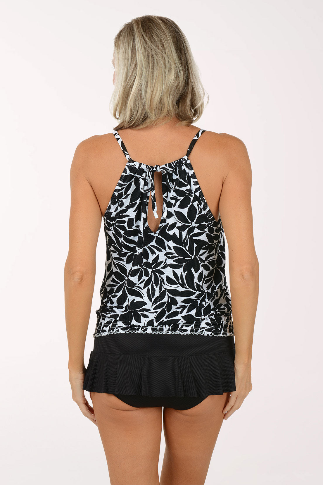 Woman wearing a black and white floral tankini set on a white background