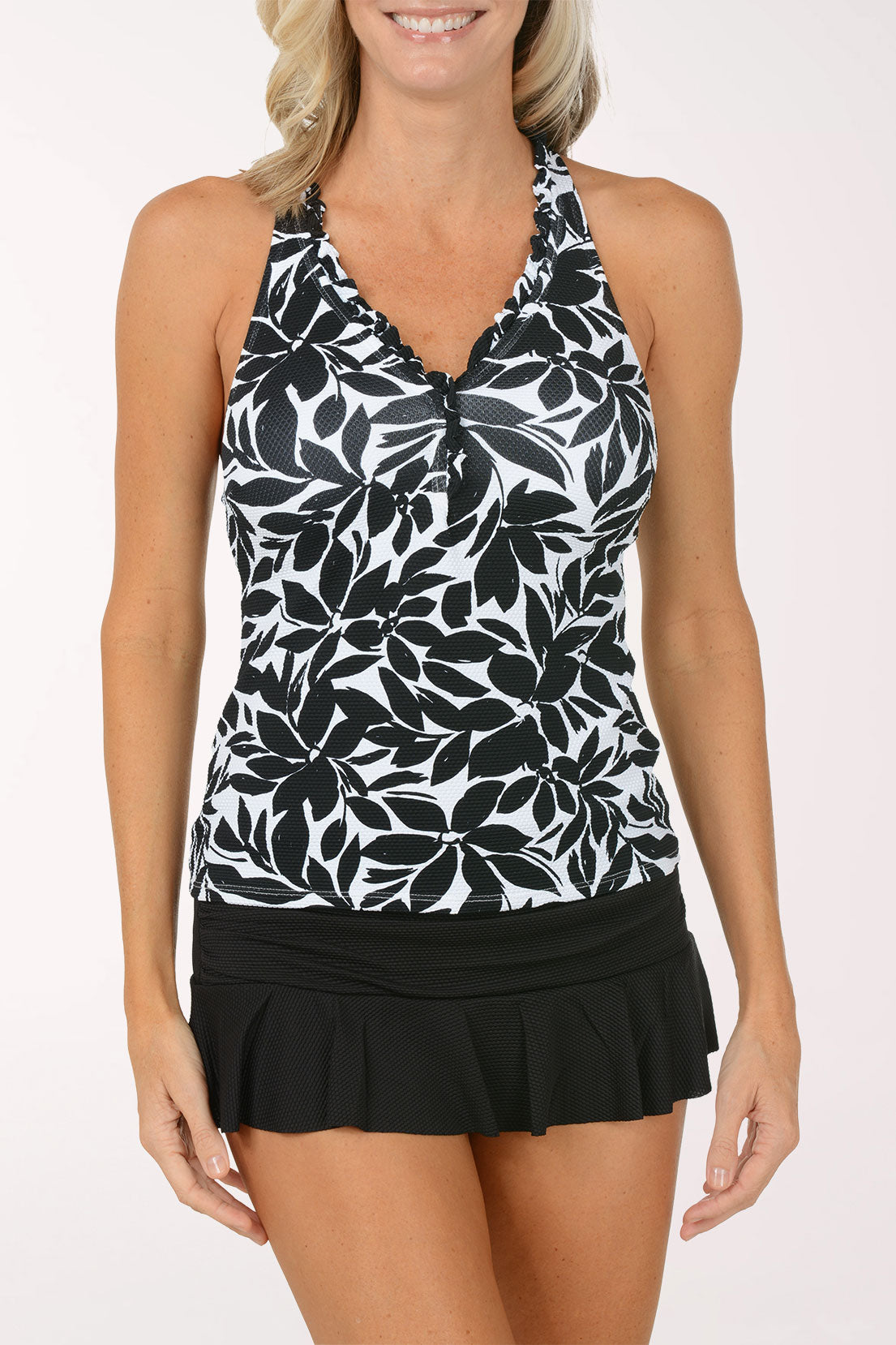 Woman wearing a black and white leaf-patterned tankini top with a black swim skirt on a white background