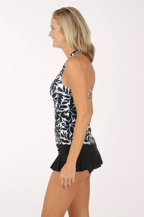 Woman wearing a black and white leaf-patterned tankini top with a black swim skirt on a white background