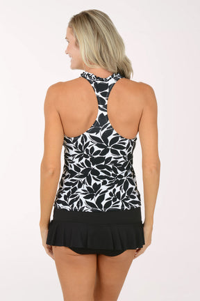 Woman wearing a black and white leaf-patterned tankini top with a black swim skirt on a white background