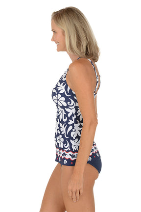 A woman wearing a navy and white tropical print tankini swim top. Side shot.