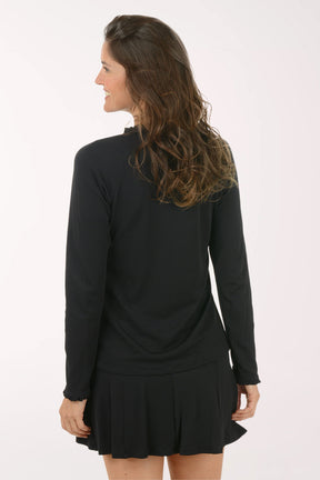 Woman wearing a black long-sleeve top and skirt on a white background. Back shot.