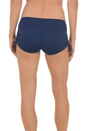 A woman wearing a navy swim boxer. Back shot.