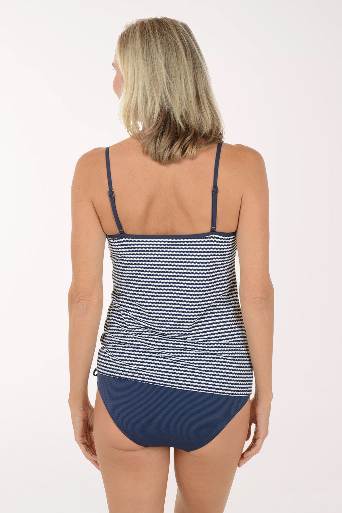 Woman wearing a blue and white striped tankini on a white background. Back shot.