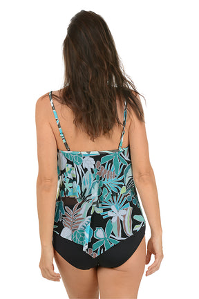 Woman wearing a floral tank top and black shorts on a white background. Back shot.