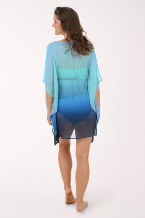 Woman wearing a blue and green gradient cover-up dress on a white background. Back shot.