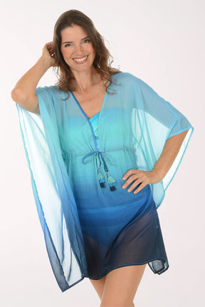 Woman wearing a blue and green gradient cover-up dress on a white background. Close up shot.