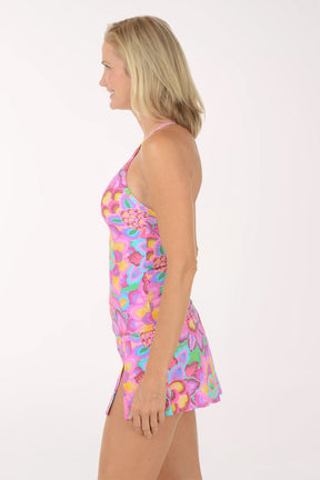 Woman wearing a colorful floral tankini top on a white background. Side shot.