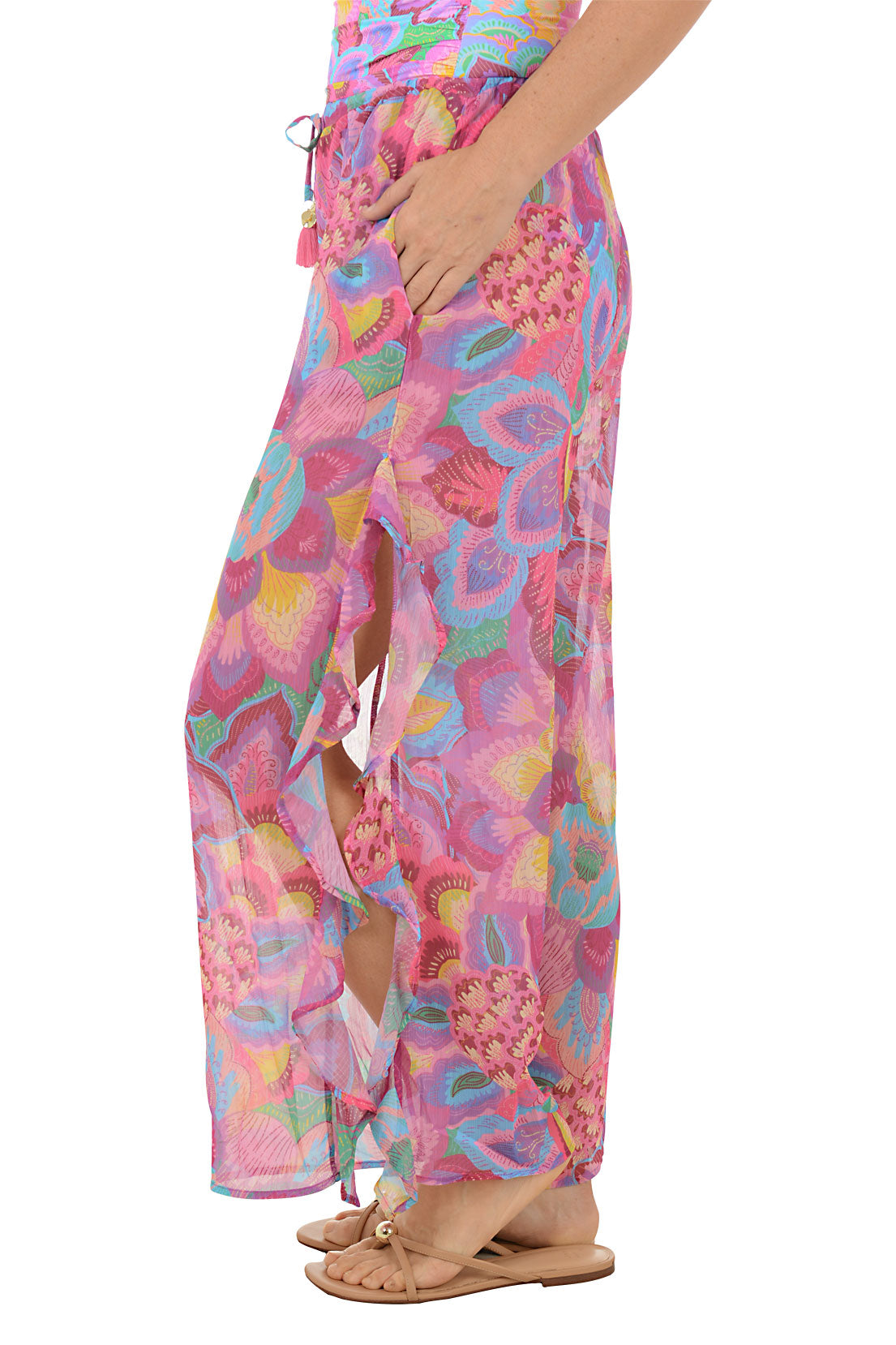 Person wearing a colorful floral wide-leg pants on a white background. Side shot.