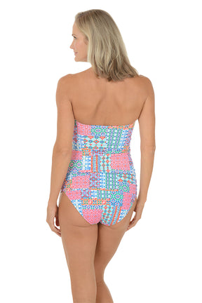 A woman wearing a multli-colored bandeau tankini top swimsuit. Back shot.