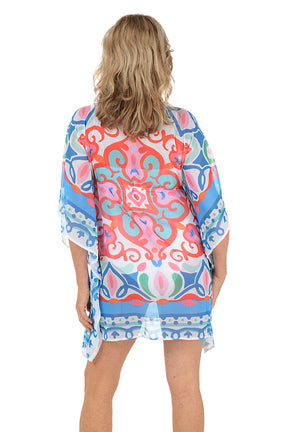 A woman wearing a multi-colored caftan over a white swimsuit. Back shot.