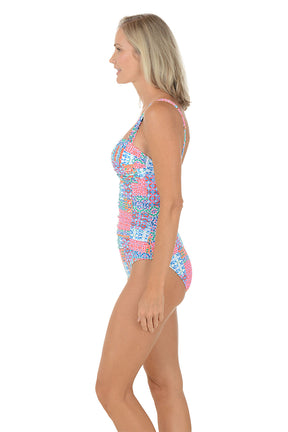A woman wearing a multi colored one piece swim suit. Side shot.