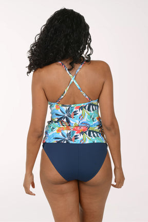 Woman wearing a colorful floral tankini top and navy blue bottoms on a white background