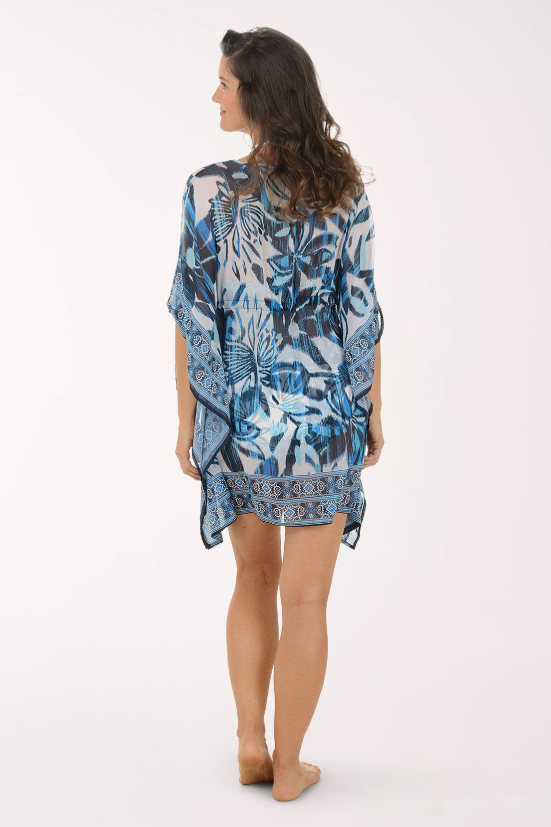 Woman wearing a blue floral patterned robe on a white background. Back shot.