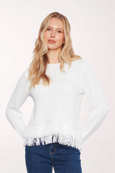 Woman wearing a white crew neck sweater with a fringe detail on the hem
