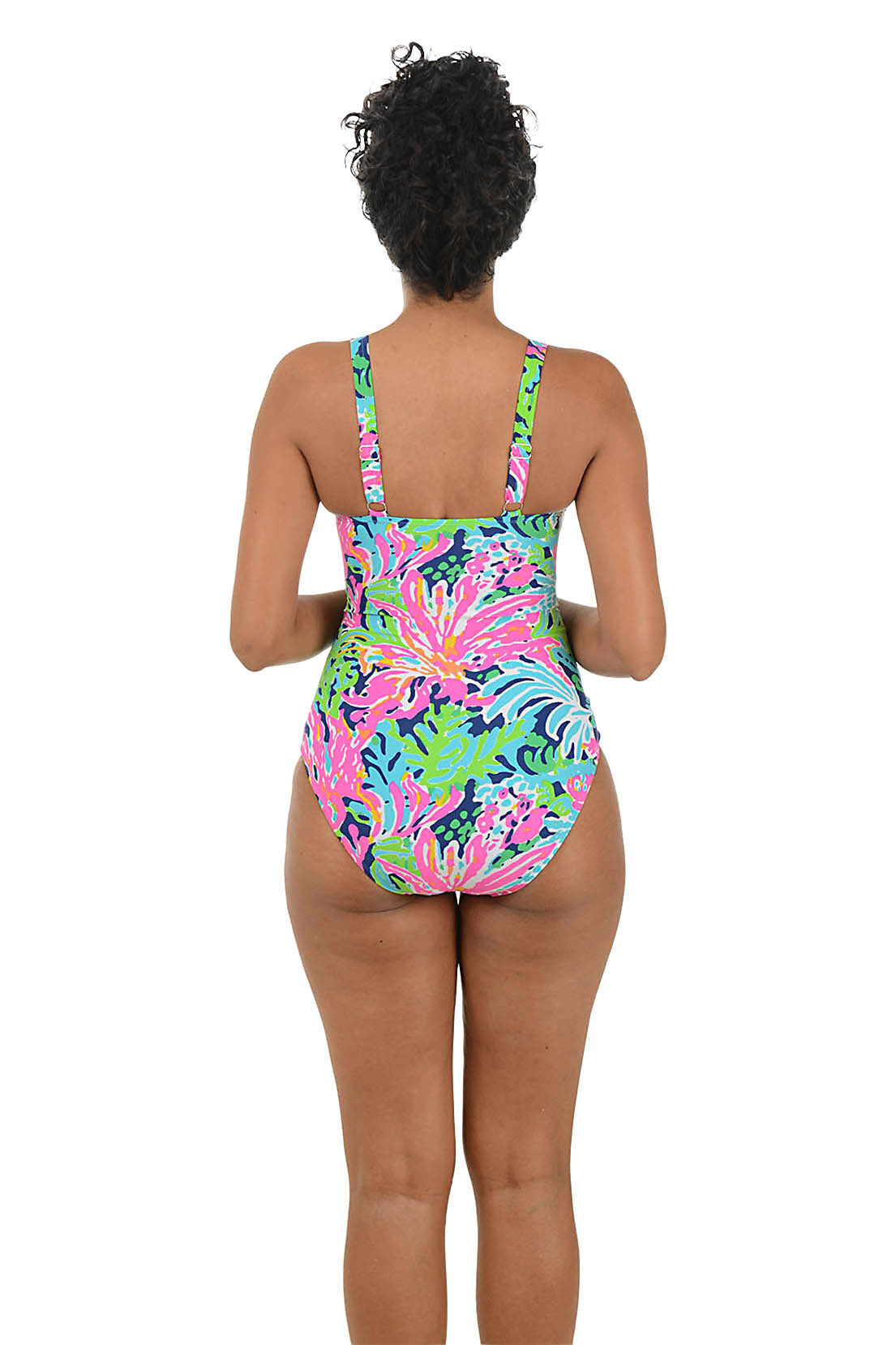 Woman wearing a colorful one-piece swimsuit on a white background. Back shot.