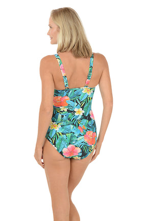 A woman wearing a muli-colored one piece swimsuit with a floral detail. Back shot.