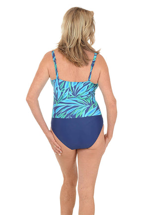 Woman wearing a blue and green patterned one piece with navy bottoms on a white background. Back shot.