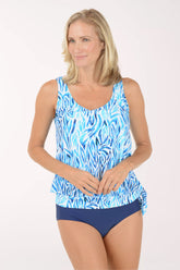 Woman wearing a blue and white patterned tankini top and navy bottoms on a white background