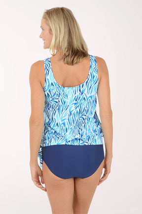 Woman wearing a blue and white patterned tankini top with a matching high-waisted bottom on a white background. Back shot.