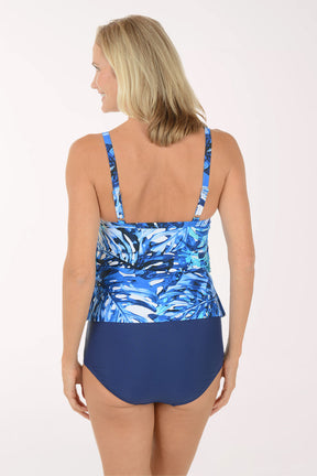 Woman wearing a blue floral tankini top and navy high-waisted bottoms on a white background. Back shot.
