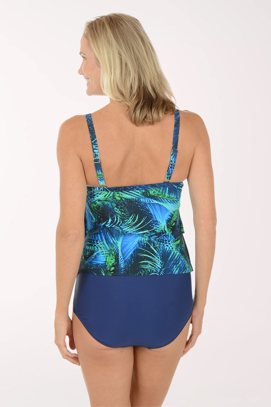 Woman wearing a blue and green leaf-patterned swimsuit on a white background. Back shot.