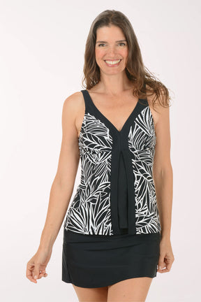 Woman wearing a black and white patterned top on a white background.