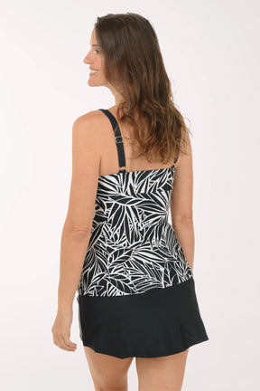 Woman wearing a black and white patterned top on a white background. Back shot.