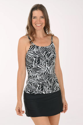 Woman wearing a black and white leaf-patterned tank top with a black skirt on a white background.