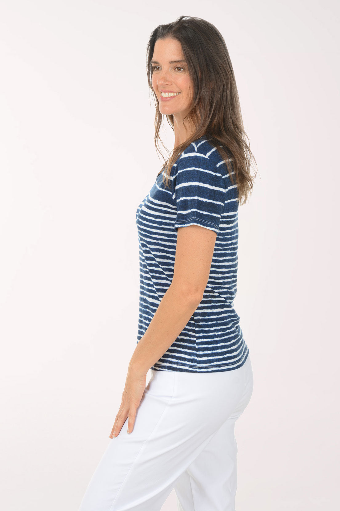 Woman wearing a blue and white striped shirt and white pants on a white background