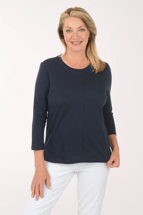 Woman wearing a navy blue top and white pants on a white background