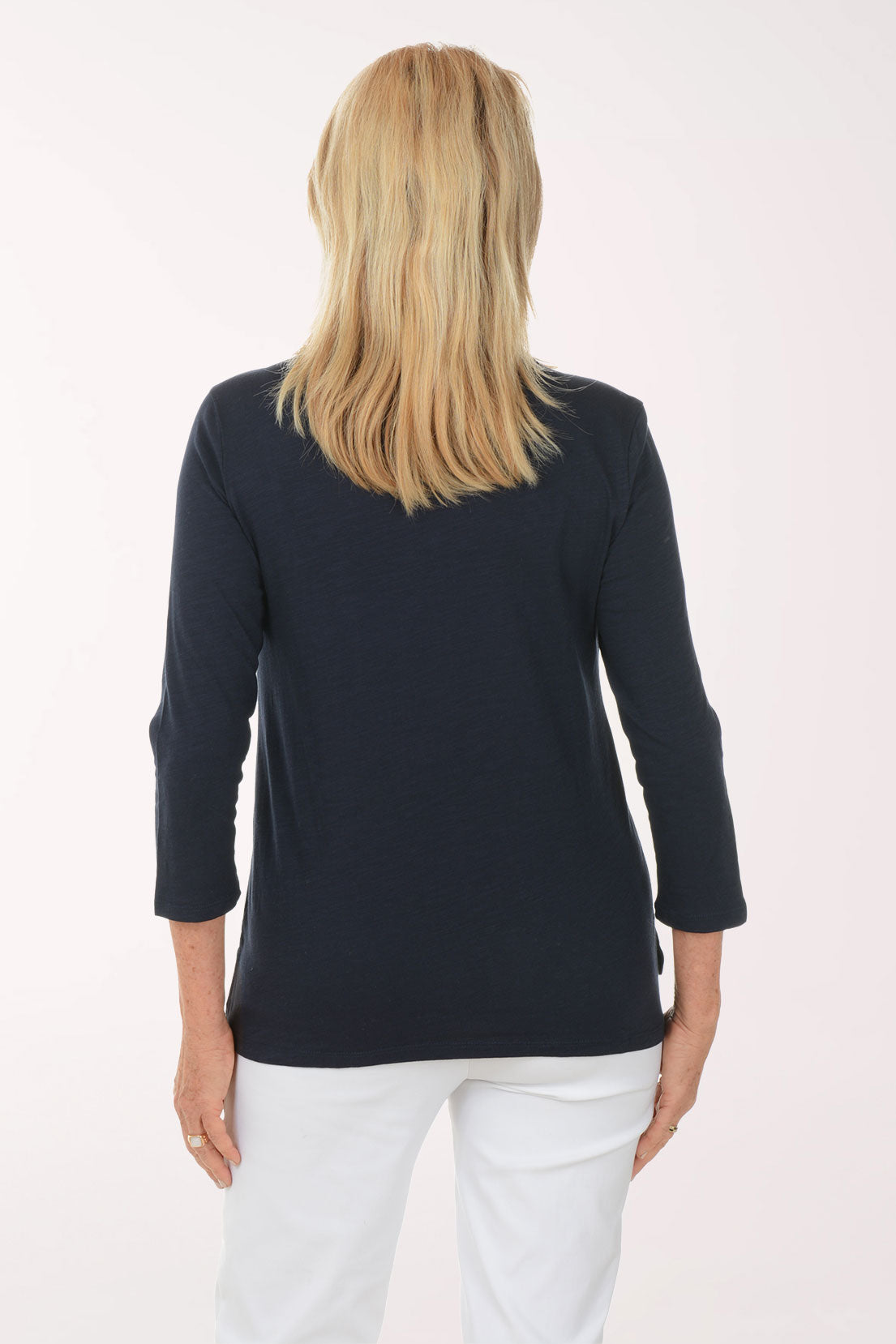 Woman wearing a navy blue top and white pants on a white background
