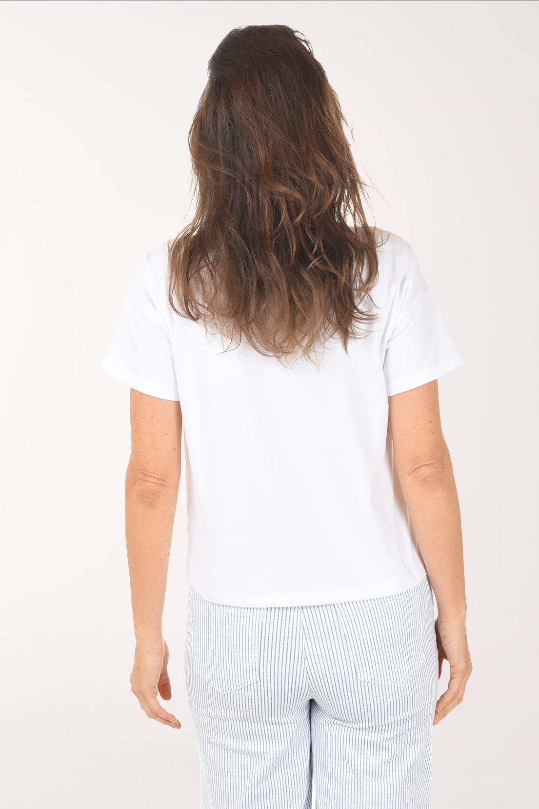 Woman wearing a white t-shirt with a graphic design on a plain background